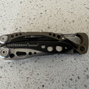 Tan Leatherman Skeletool in closed position with the carabiner on the right